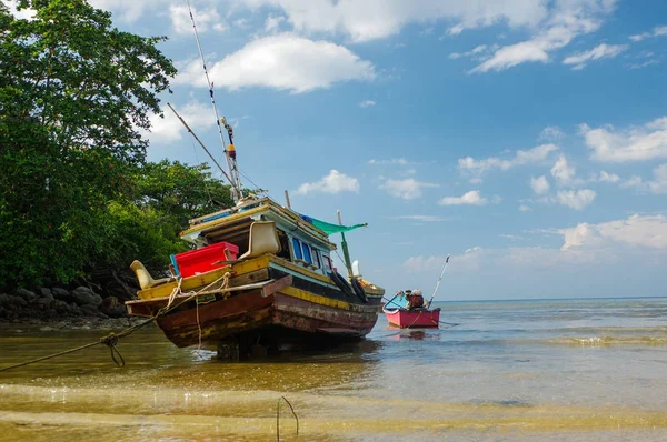 Tay eski balıkçı küçük teknede düşük tide sığlık içinde. Tayland Phuket.