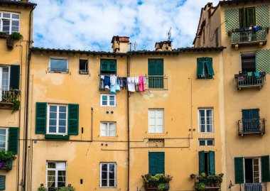 Lucca / İtalya - 29 Mayıs 2018: Tarihi ortaçağ kentinin merkezinde, Piazza dell 'Anfiteatro' da pencereleri olan eski evlerin manzarası.