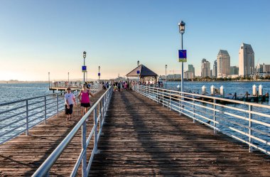 Coronado, CA / USA - 24 Temmuz 2015: Coronado Ferry Landing, öğleden sonra. Yolcular onları San Diego 'ya götürecek feribotu bekliyorlar. San Diego silueti sağda..