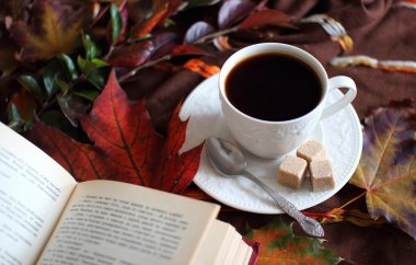Bir fincan kahve arka planda sonbahar yaprakları.
