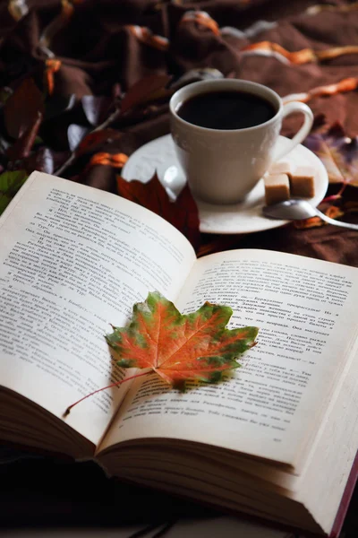 Bir fincan kahve arka planda sonbahar yaprakları.