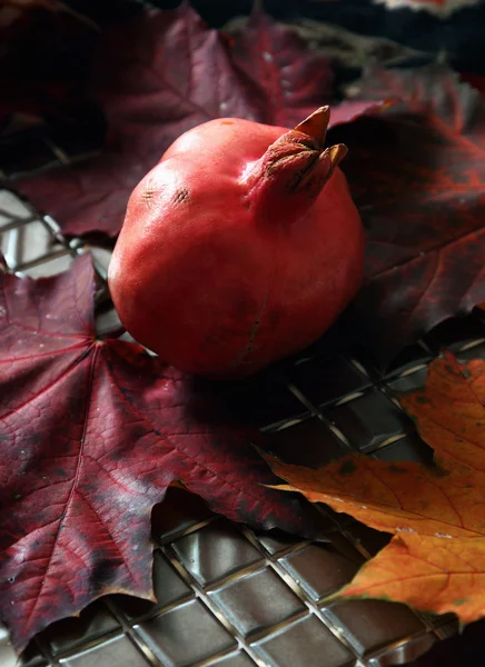 Reifer Granatapfel auf einem Hintergrund aus Blättern. — Stockfoto