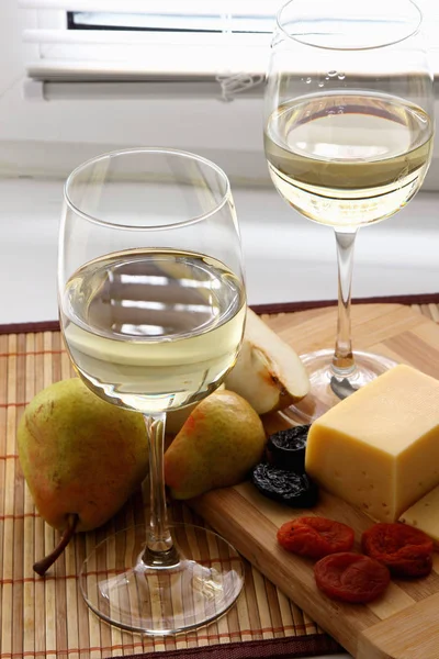 Glasses with white wine and cheese with fruit. — Stock Photo, Image