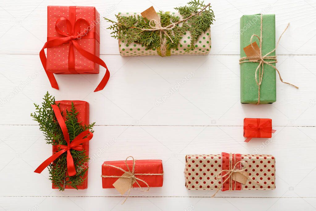 Christmas composition made of red, green, brown crafted Christmas gifts on white wooden table background. Christmas, Xmas, winter, new year concept. Flat lay, frame, top view, copy space.
