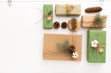 Çam kozalaklarından, brançlardan, ağaç halkalarından, beyaz masa üzerinde plastik olmayan el yapımı hediyelerden oluşan Noel kompozisyonu. Noel, Noel, Noel, kış, yeni yıl, sıfır atık kavramı. Üst görünüm, fotokopi alanı, düz alan.