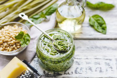 Yeşil fettuccine ve Pesto sosu eski kaşık içinde cam bir kavanoz pesto sosu ve kırsal beyaz ahşap masa malzemeleri. Fetuçin, makarna, bruschetta yapmak için geleneksel İtalyan pesto tarifi.