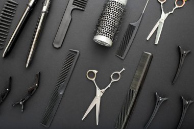 Kuaför aletleriyle düz kompozisyon: makas, tarak, siyah arkaplanda saç ütüsü. Çerçeve. Kuaför servisi. Güzellik salonu servisi. Kuaför Seti.