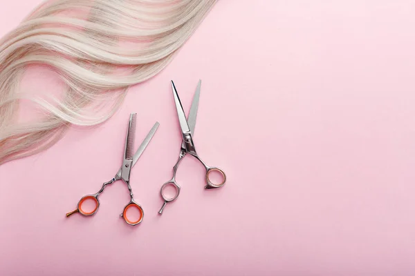 Scissors and other hairdresser's accessories and strand of blonde hair on pink background. Flat lay with space for text. Hairdresser service. Beauty salon service — ストック写真