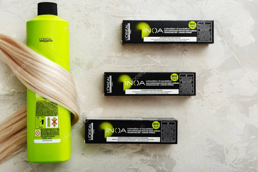 Set of cosmetics for Hair Coloristics Inoa by L'oreal professionnel Paris. Inoa Loreal oxidant riche and professional hair dye in boxes for hairdressers with strand of blonde hair on gray background