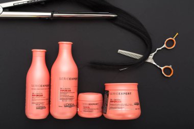 L 'oreal Profesnel Paris Serie Expert Inforcer saç profesyonel ürünleri. Saç için Loreal şampuan kremi kremi. Kuaför makası, saç ütüsü Babyliss. Siyah arkaplan üzerinde düz uzandı