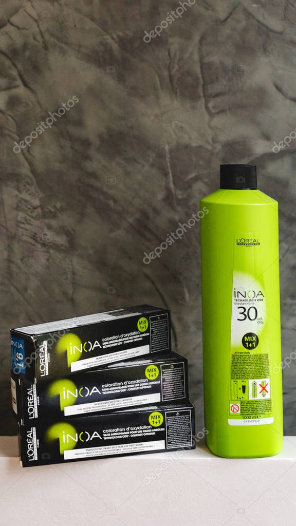 Set of cosmetics for Hair Coloristics Inoa by L'oreal professionnel Paris. Inoa Loreal oxidant riche and professional hair dye in boxes for hairdressers with strand of blonde hair on gray background