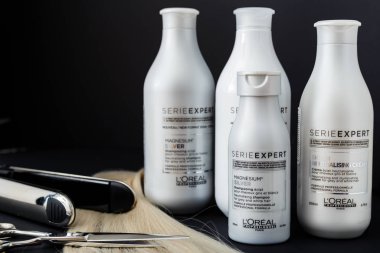 L 'oreal Profesnel Paris Serie Uzmanı Gümüş Saçlı Profesyonel Yapımcılar. Saç için Loreal şampuan kremi maskesi. Profesyonel kuaför makası, saç ütüsü ve siyah arka planda sarı saç tutamı.
