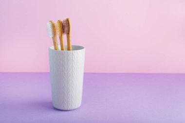 Cam kaplı doğal bambu diş fırçaları pembe arka planda. Biyo-çözünebilir doğal bambu diş fırçası. Çevre dostu, sıfır atık, diş bakımı, plastiksiz konsept. Metin için alanı kopyala