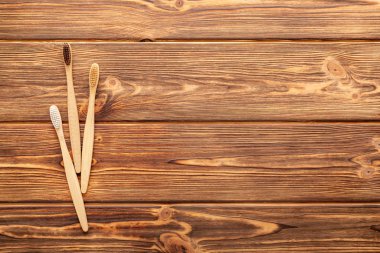 Tahta arka planda bambu diş fırçaları. Fotokopi alanı olan düz bir yer. Doğal banyo ürünleri. Biyo-çözünebilir doğal bambu diş fırçası. Çevre dostu, sıfır atık, diş bakımı plastik içermeyen konsept