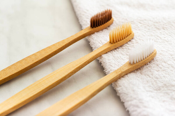 Bamboo toothbrushes on white towel on marble background. Flat lay copy space. Natural bath products. Biodegradable natural bamboo toothbrush. Eco friendly, Zero waste, Dental care Plastic free concept