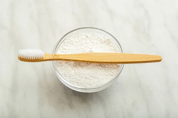 Bamboo toothbrush, dentifrice tooth powder on white marble background. Biodegradable natural bamboo toothbrush. Eco friendly, Zero waste, Dental care Plastic free concept. Close up