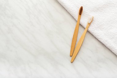 Bambu diş fırçaları, beyaz havluyla bambu bitkisi, mermer arka plan. Düz yatıyordu. Doğal banyo ürünleri. Biyolojik çözünür doğal bambu diş fırçası. Çevre dostu, sıfır atık, diş bakımı plastiksiz kavram.