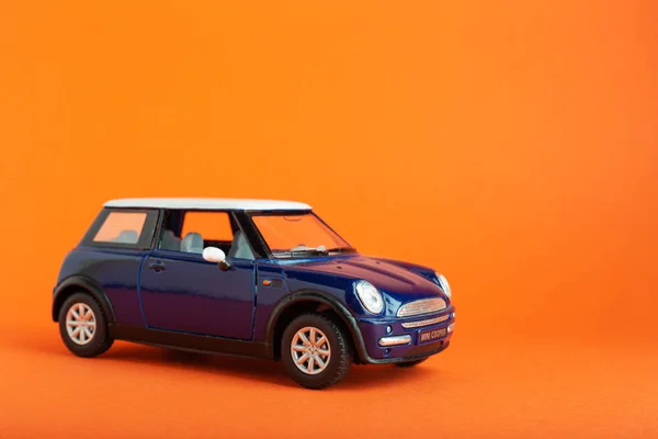 Mini Cooper S Leksaksbil på Lush Lava orange bakgrund med kopieringsutrymme för text. Resor koncept färgat i trendiga färger. Semester resa äventyr symbol eller bil hyra koncept — Stockfoto