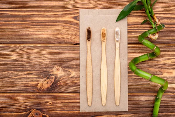 Bamboo toothbrushes, bamboo branch on wooden background. Flat lay copy space. Natural bath products. Biodegradable natural bamboo toothbrush. Eco friendly, Zero waste, Dental care Plastic free concept — Stock Photo, Image