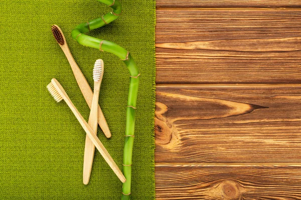 Bamboo toothbrushes, bamboo branch on wooden background. Flat lay copy space. Natural bath products. Biodegradable natural bamboo toothbrush. Eco friendly, Zero waste, Dental care Plastic free concept