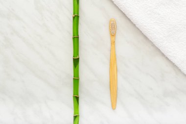 Bambu diş fırçaları, beyaz havluyla bambu bitkisi, mermer arka plan. Düz yatıyordu. Doğal banyo ürünleri. Biyolojik çözünür doğal bambu diş fırçası. Çevre dostu, sıfır atık, diş bakımı plastiksiz kavram.
