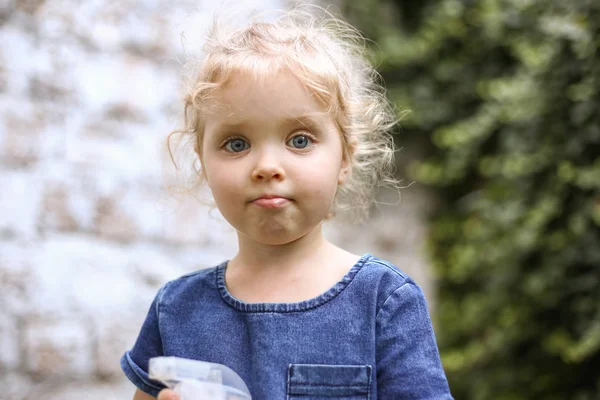 巻きブロンドの髪と古典的な青い色のドレスで3 〜 4年の青い目を持つ小さな美しいヨーロッパの女の子の肖像画、トレンディーな色2020 。春か夏に庭で遊ぶ女の子 — ストック写真
