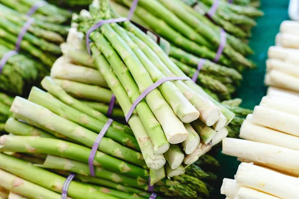 Bunches of fresh raw green organic asparagus vegetables for sale at farmers market. Vegan food concept. Stock photo green Asparagus Close up. Raw white and green asparagus at market.