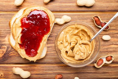 Fıstık ezmeli tost sandviç. Kahverengi ahşap arka planda kahvaltı hazırlamak için fıstık ezmesi, reçel ve fıstık. Kremalı fıstık ezmesi düzdü..