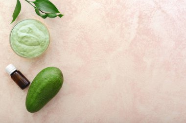 Avocado face mask in glass jar with leaves and avocado, oil. Homemade nourishing mask made from mashed avocado. Diy Homemade cosmetics recipe, skin care concept. Avocado Flat lay on pink background.