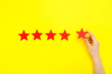 5 stars increase rating, customer experience concept. Hand of client show putting 5 star symbol to increase Service rating. five red stars excellent rating on yellow background. Satisfaction concept
