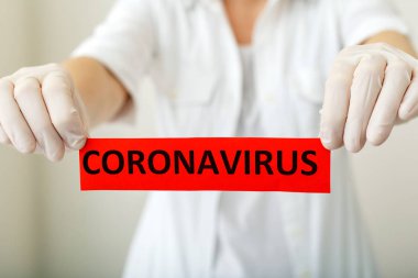 Coronavirus, kırmızı uyarı işareti. Beyaz önlüklü ve eldivenli doktorların elinde Coronavirus yazıyor. Çin Coronavirüsü 2020, Wuhan virüsü, Çin Coronavirüs salgını gribi..