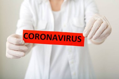 Coronavirus, kırmızı uyarı işareti. Beyaz önlüklü ve eldivenli doktorların elinde Coronavirus yazıyor. Çin Coronavirüsü 2020, Wuhan virüsü, Çin Coronavirüs salgını gribi..