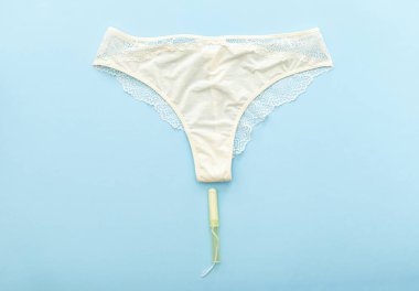 Adet tamponlu beyaz külot pastel renkli mavi arka planda güve döngüsü için. Küloduyla yatıyordu. Regl, kadın hijyeni, kadın sağlığı, kritik günler konsepti