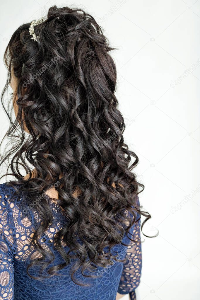 Weave, braid tail hairstyle. Hairstyle on brown hair woman with long hair on a gray background. Professional hairdressing services.Hair styling, making braid with hairpin