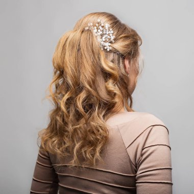 Kıvırcık saç stili. Beyaz arka planda uzun saçlı, sarı saçlı bir kadının saç stili. Profesyonel kuaför servisi. Saç stili, saç tokasıyla örgü. Boşluğu kopyala