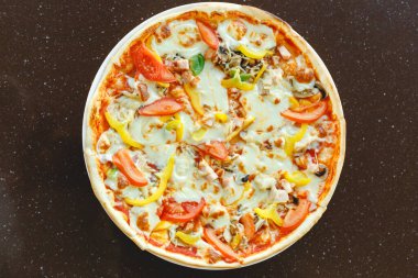 Biberli ve domatesli nefis pizza. Koyu masa, üst manzara. Mozarella peynirli sıcak İtalyan pizzası.