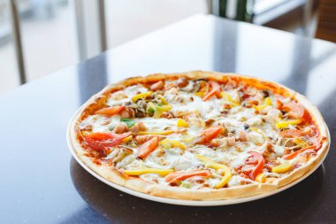 Biberli ve domatesli lezzetli pizza. Kahve ya da İtalyan restoranında servis ediliyor. Peynirli sıcak pizza.