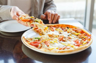 Lezzetli pizza. Kafkasyalı adam İtalyan pizzasından lezzetli bir parça alıyor. Kafede, restoranda ya da evde mozzarella peyniri ile. Fast food pizza..