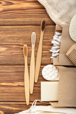 Sıfır atık ev ürünü. Bambu diş fırçaları, sabun, tahta arka planda pamuk çubukları. Doğal banyo ürünleri. Fotokopi alanı olan düz bir alan. Çevre dostu, sıfır atık, plastiksiz diş bakımı..