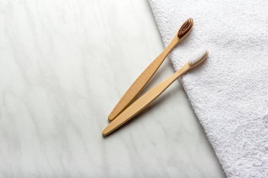 Bambu diş fırçaları beyaz havlu ve mermer arka plan. Düz kopya alanı. Doğal banyo ürünleri. Biyolojik çözünebilir doğal bambu diş fırçası. Çevre dostu, sıfır atık, diş bakımı plastik konsepti..