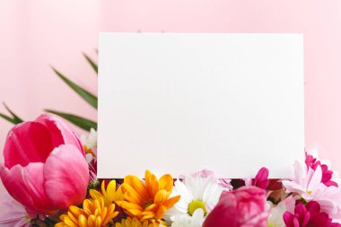 Çiçekler tebrik taklidi yapar. Pembe arka planda bir buket çiçekli tebrik kartı. Metin, çerçeve modeli için yeri olan beyaz boş kart. Bahar festivali çiçek konsepti, hediye kartı.