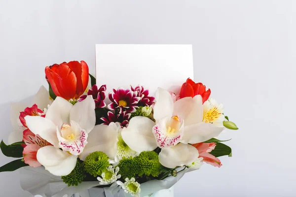 Flowers mock up congratulation. Congratulations card in bouquet flowers on white background. Blank card with space for text, frame mockup. Spring festive flower concept with orchids, tulips,gift card