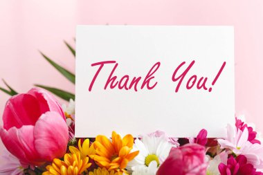 Teşekkür kartı pembe arka planda güzel çiçek buketi. Metin için boşluk, davetiye için çerçeve modeli. Bahar şenliği çiçekleri.