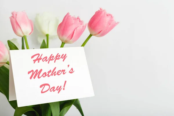 행복 한 어머니들은 하얀 배경에 꽃다발을 놓고 선물 카드로 문자 메시지를 보냅니다. 엄마한테 온 카드네요. 꽃 배달, 여성을 위한 꽃으로 축하 카드. 분홍색 튤립으로 인사 카드. — 스톡 사진