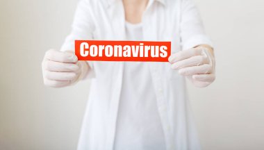 Coronavirus salgını, kırmızı uyarı işareti Coronavirus 'un beyaz önlüklü, eldivenli, yüzü tıbbi maskeli doktorların elinde olduğu yazı. Karantina koronavirüsü salgını. Coronavirus salgını gribi. Uzun pankart.
