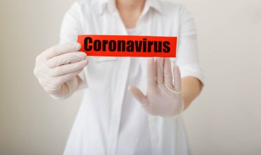 Coronavirus salgını, kırmızı uyarı işareti Coronavirus 'un beyaz önlüklü, eldivenli, yüzü tıbbi maskeli doktorların elinde olduğu yazı. Karantina koronavirüsü salgını. Coronavirus salgını gribi. Uzun pankart.