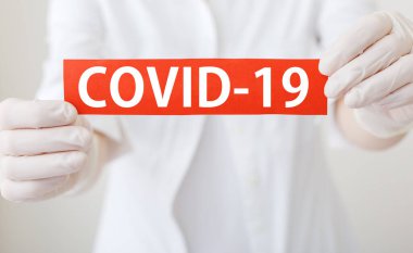 COVID-19 Coronavirus, COVID-19 yazılı kırmızı uyarı işareti beyaz önlüklü, eldivenli doktorların elinde, tıbbi maskeyle karşılaşıyorlar. Karantina Coronavirüs Salgını Epidemik Etkisi Etkisi. COVID19 Sağlık Bakım Konsepti