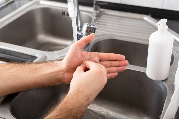 Man washing hands with antibacterial soap and water in metal sink for corona virus prevention. Hand hygiene, health care, medical concept. Hand skin disinfection protect from Coronavirus covid 19.