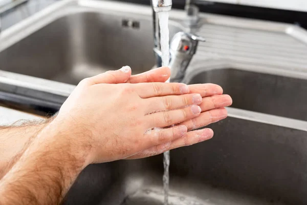 Man washing hands with antibacterial soap and water in metal sink for corona virus prevention. Hand hygiene, health care, medical concept. Hand skin disinfection protect from Coronavirus covid 19.