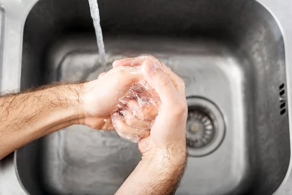 Man washing hands with antibacterial soap and water in metal sink for corona virus prevention. Hand hygiene, health care, medical concept. Hand skin disinfection protect from Coronavirus covid 19.